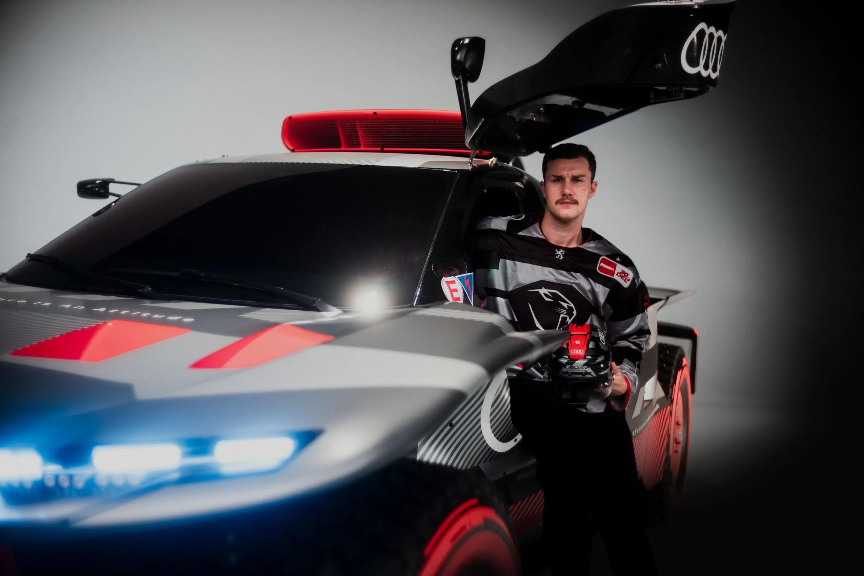 Kevin Maginot präsentiert das neue Warmup-Jersey in einem Audi.