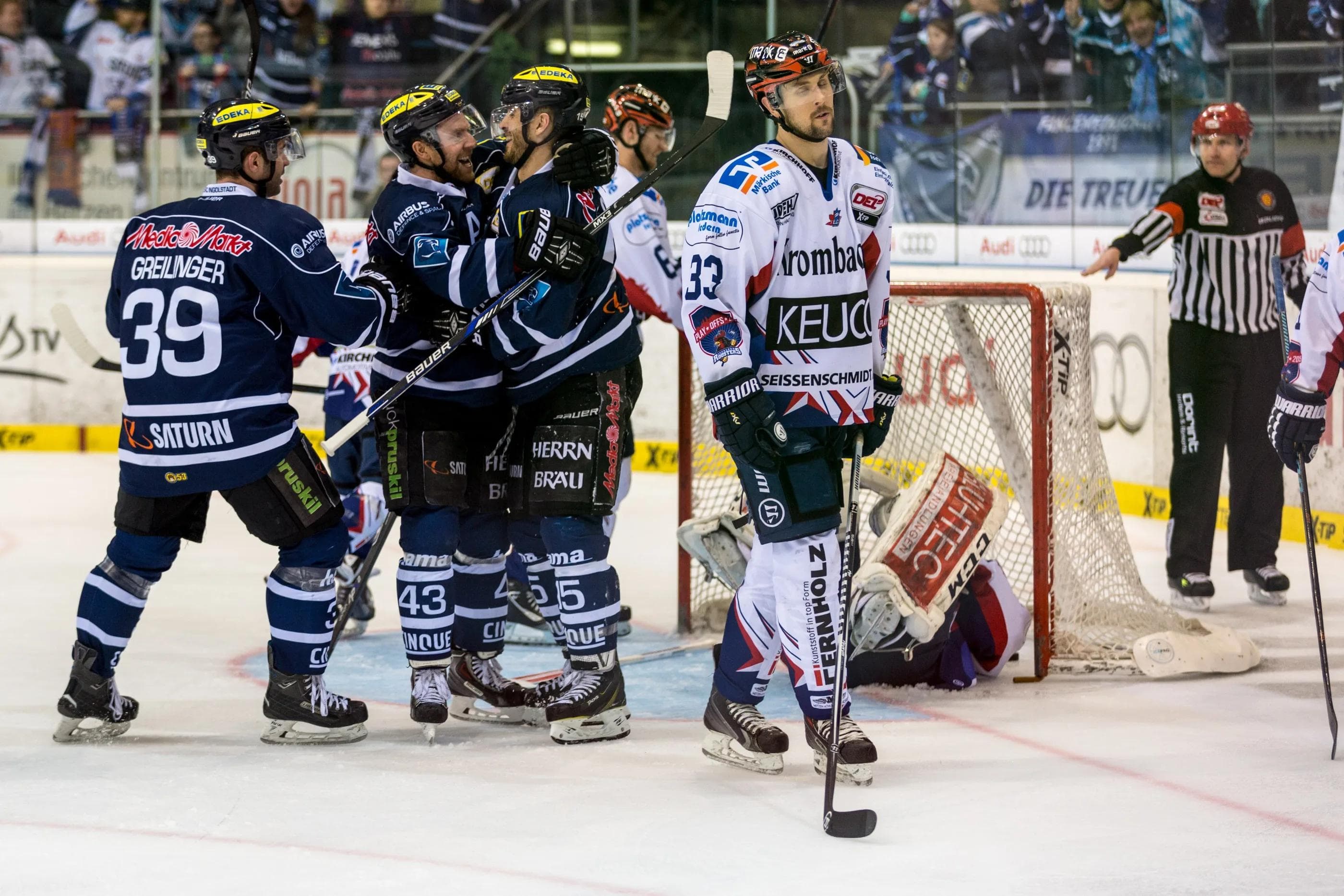 Thomas Greilinger (von links) und Derek Hahn jubeln mit dem Torschützen John Laliberte. Iserlohns Colten Teubert fährt geknickt ab. Foto: Udo Rimmelspacher